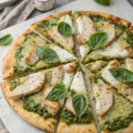 Homemade chicken pesto pizza topped with melted mozzarella, fresh basil, and cherry tomatoes on a golden crust.