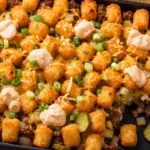 Cheeseburger Tater Tot Casserole topped with melted cheddar cheese, crispy tater tots, and ground beef in a creamy sauce baked to perfection.